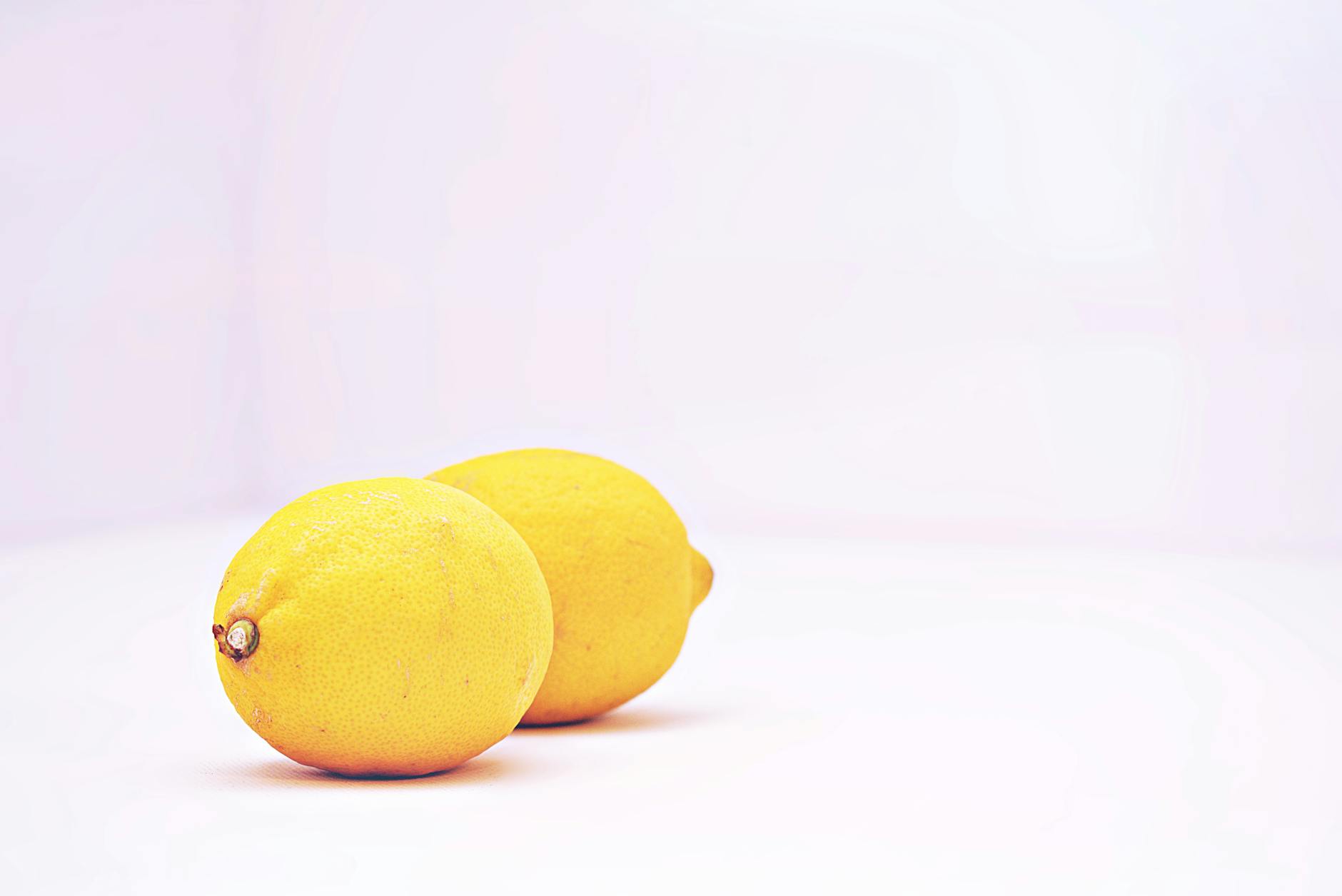 Two vibrant lemons placed against a minimalistic white background, showcasing the lemon vibrator design philosophy