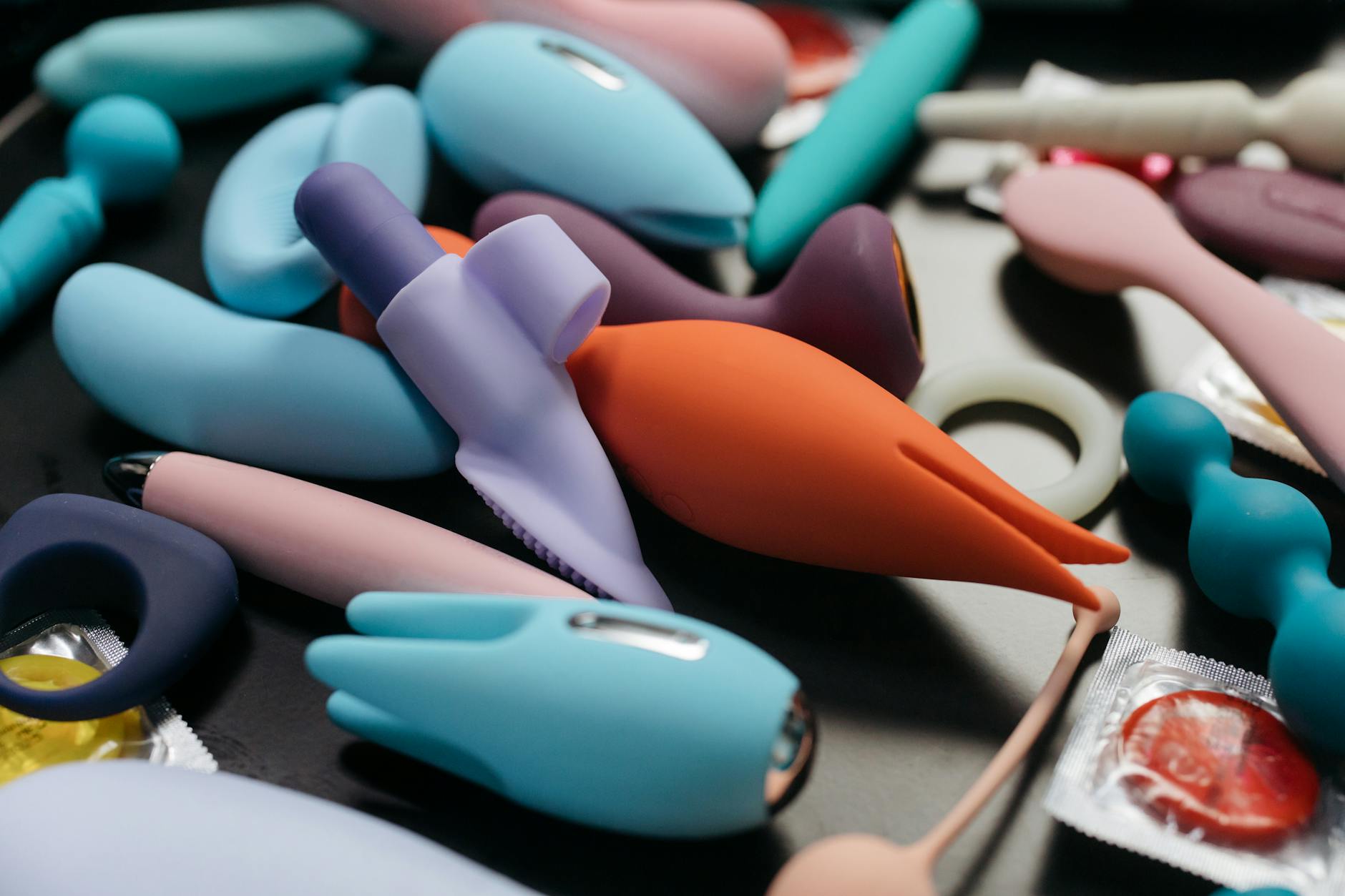 Two hands holding vibrators against a pastel background, representing pleasure tools for sensitive bodies