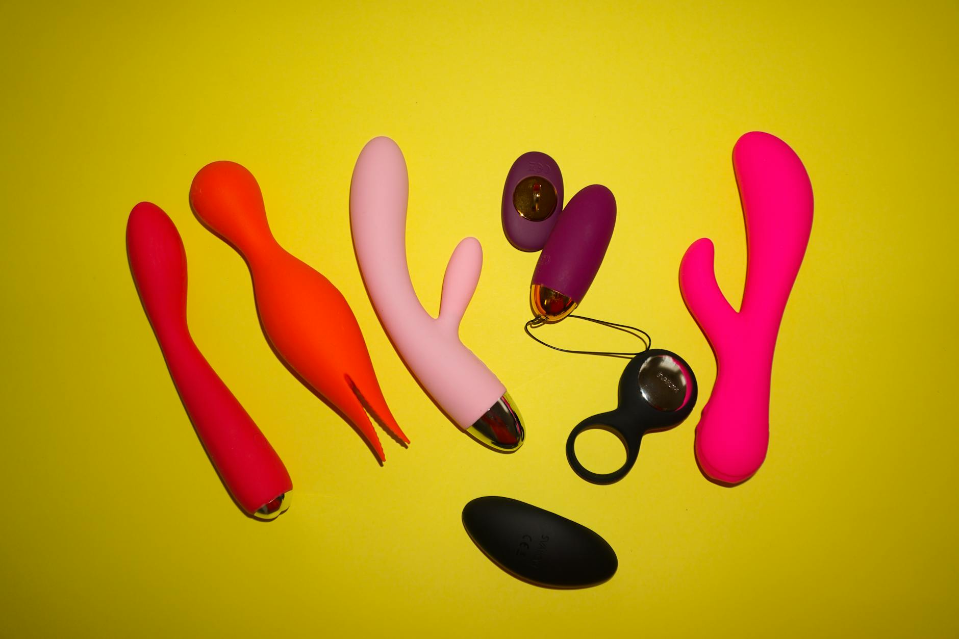 Colorful modern sex toys displayed on a bright yellow background