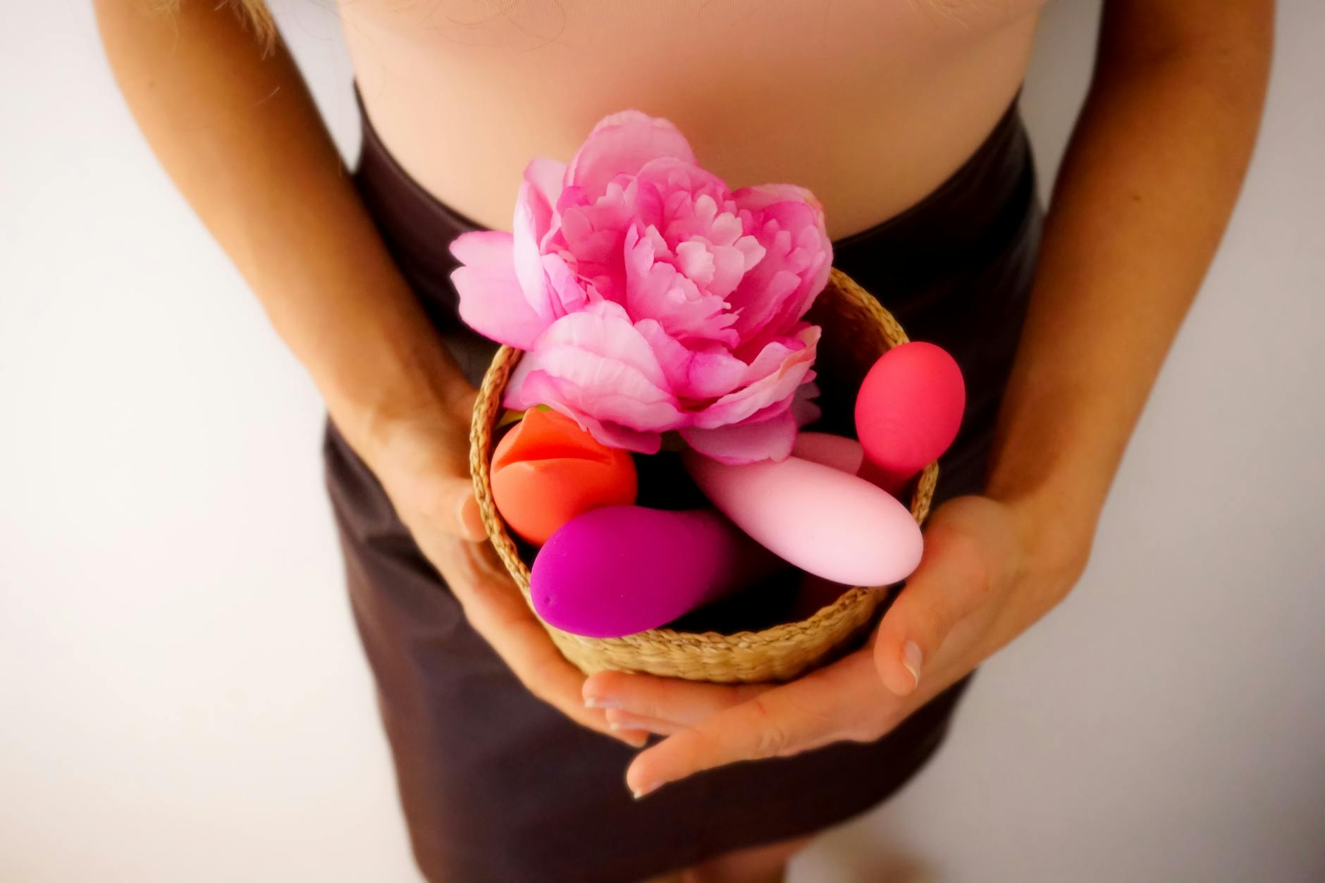 Hand reaching over a variety of colorful sex toys arranged on a table
